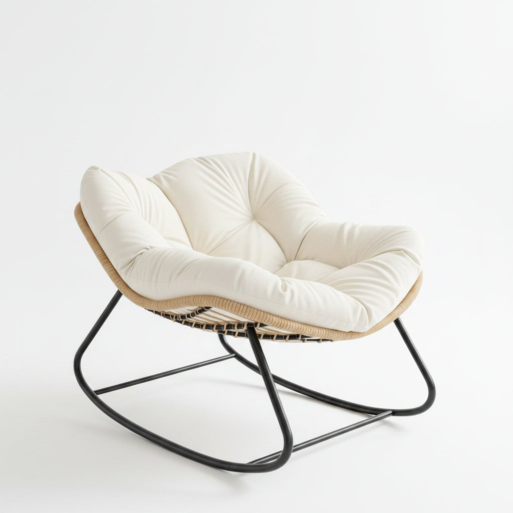A modern cushioned accent chair with a tufted cream seat and back, a natural woven rattan or wicker frame, and a black metal rocking base, set in a bright room with a window and warm sunlight.