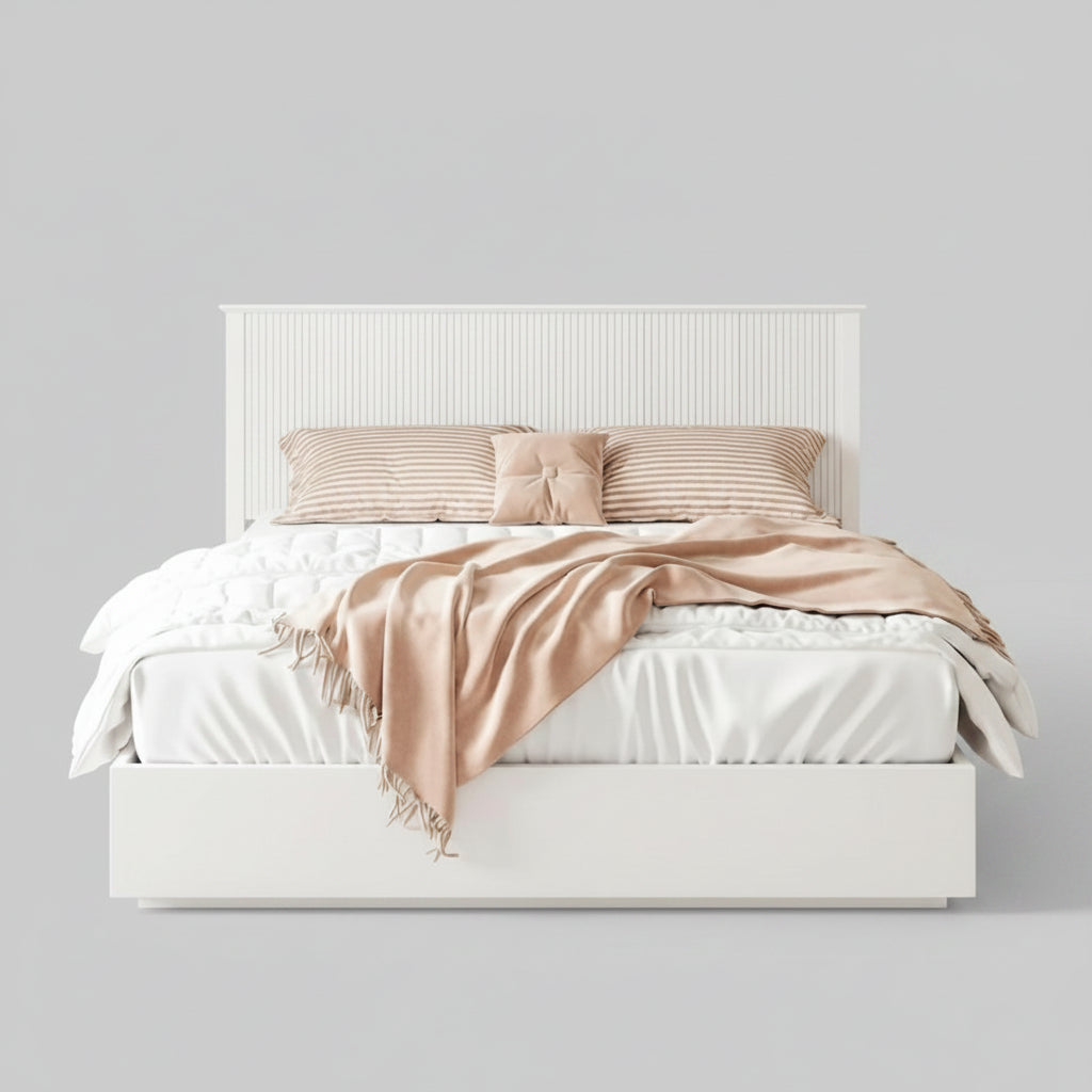 Neatly made bed with pink blanket and pillows in a bedroom setting.