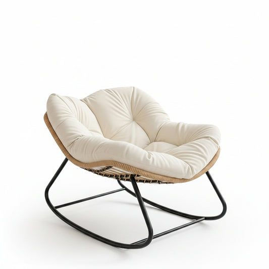A modern cushioned lounge chair with a white tufted seat and back, a natural woven rattan or wicker frame, and a black metal rocking base, placed in a luxurious, sunlit bedroom interior.